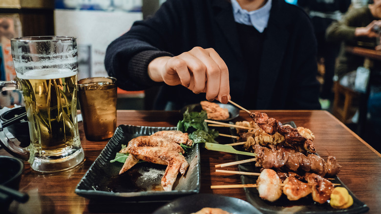 Person with food and beer at izakaya