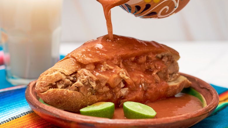 Sauce being poured on a torta ahogada