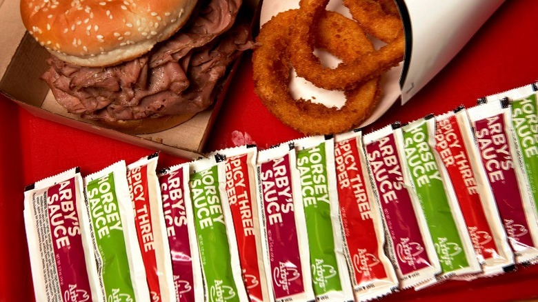 Arby's sandwich, onion rings, and packets of sauce