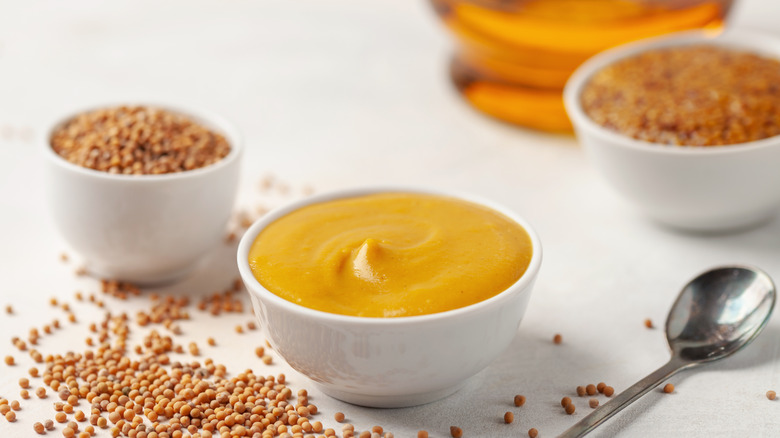 mustard sauce and seeds on white table