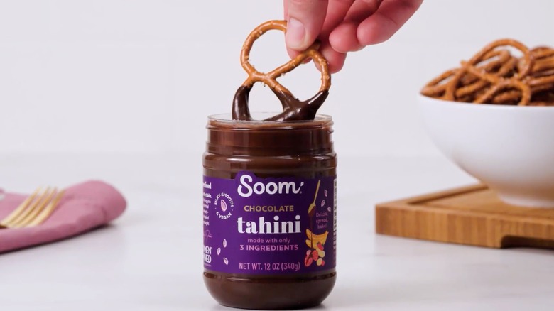 Dipping pretzel in soom chocolate tahini 