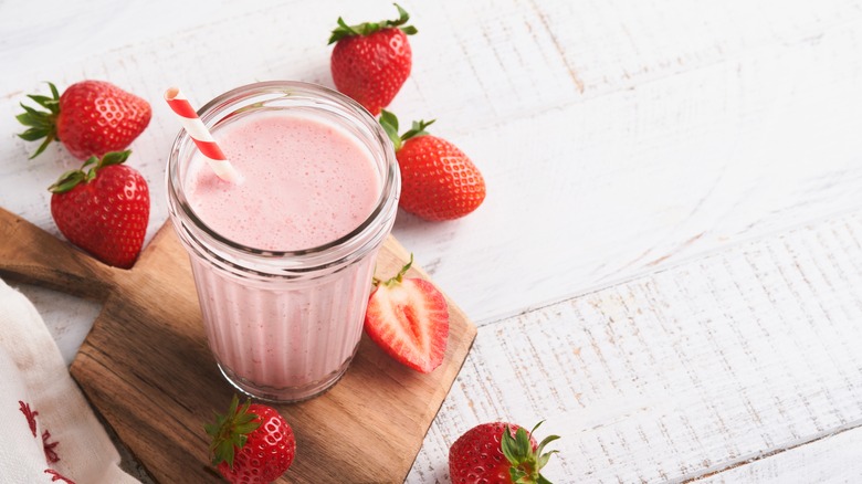 Strawberry milk in glass with strawberries around