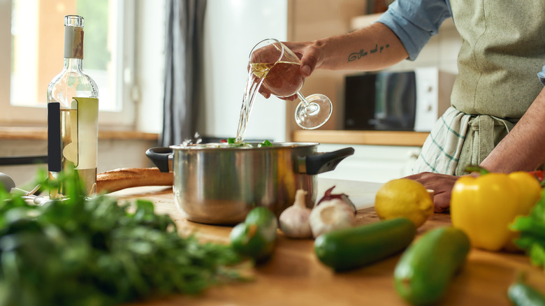 chef adding white wine to sauce