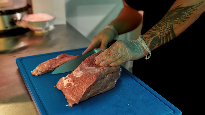 Cutting raw pork on plastic board