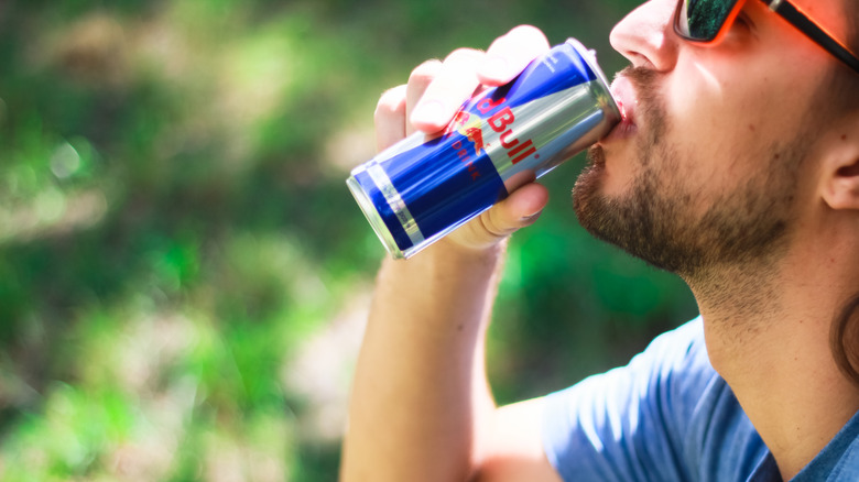 A man drinking a can of Red Bull