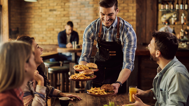 smiling waiter serving patrons tableside at a restaurant