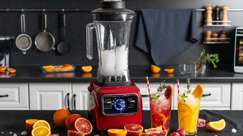 Blender full of ice surrounded by drinks.