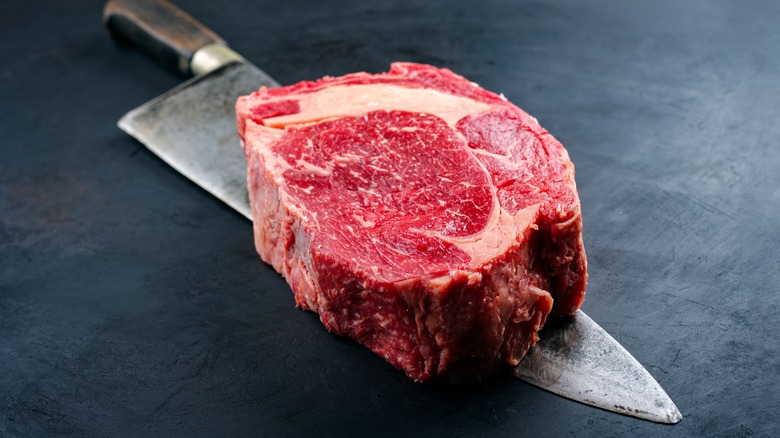 raw Delmonico steak on knife