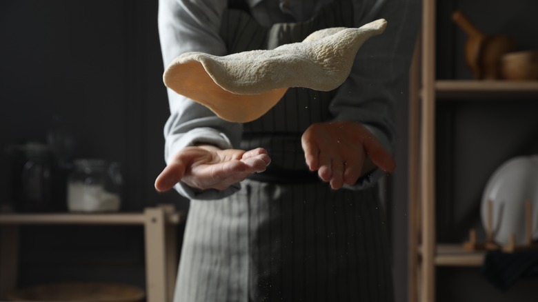 pizza dough being hand-tossed