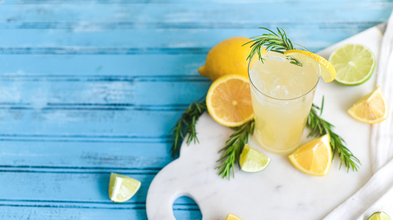 A lemon cocktail with lemon wedges and rosemary