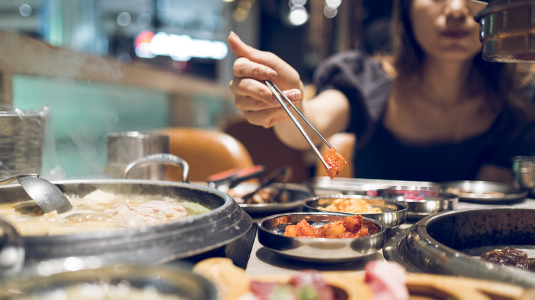 A woman picks up kimchi with chopsticks