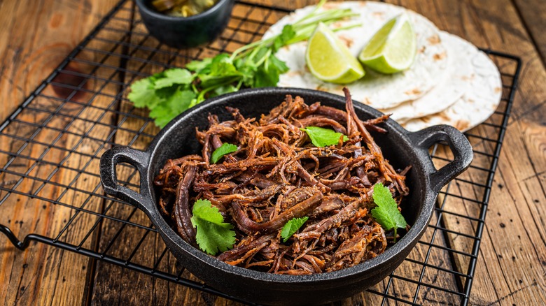 Pork carnitas meat in cast iron with tortilas