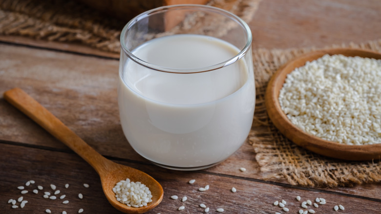 glass of sesame milk next to bowl of sesame seeds