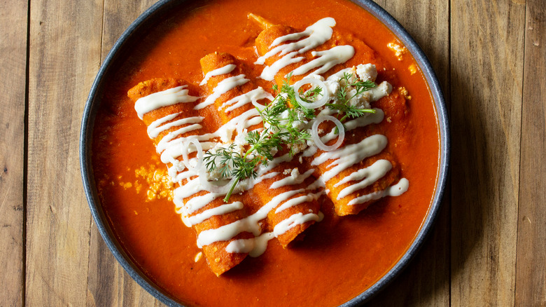 enchiladas topped with red sauce and Mexican crema