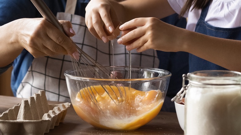 hands cracking eggs into bowl