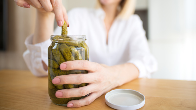 hands taking pickle out of jar