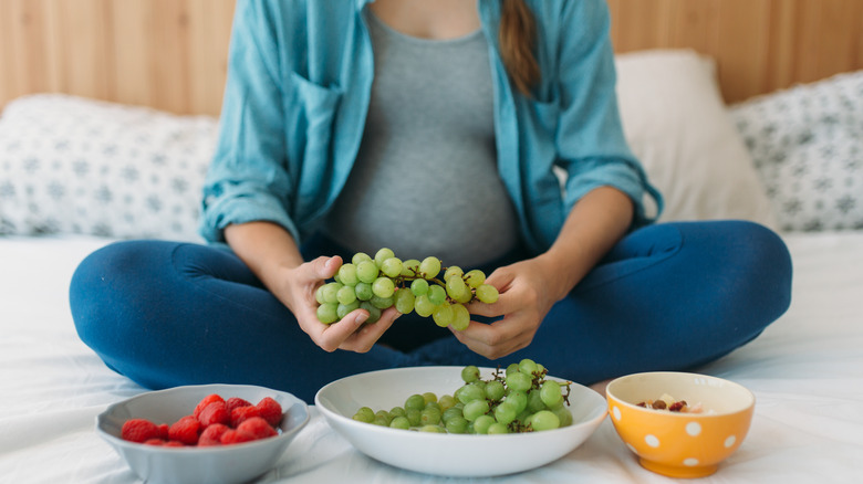 pregnant woman holding grapes