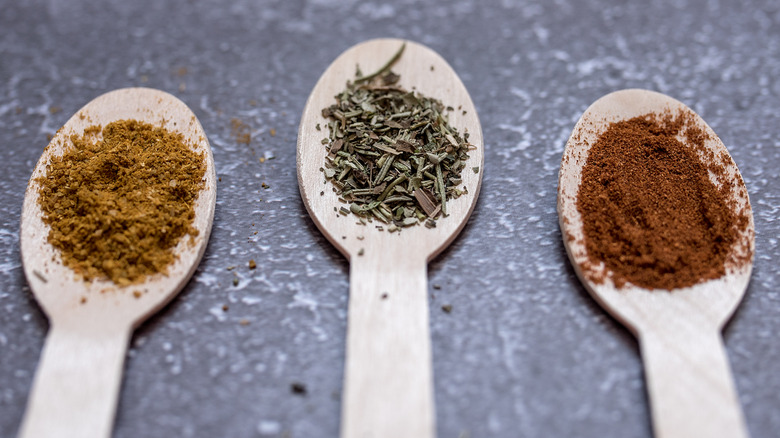 three wooden spoons with different dried spices