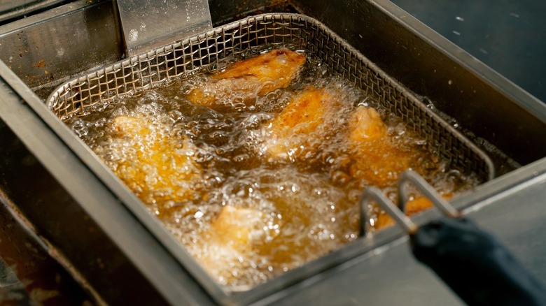 wings cooking in a fryer basket full of oil