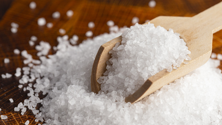 A scoop of course salt on a wooden table