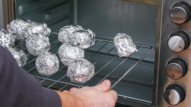 Potatoes baking on oven rack in foil