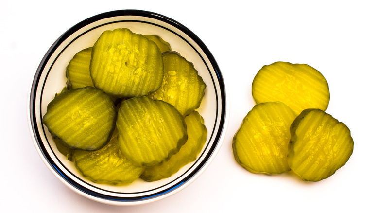 A glass bowl of pickle chips 