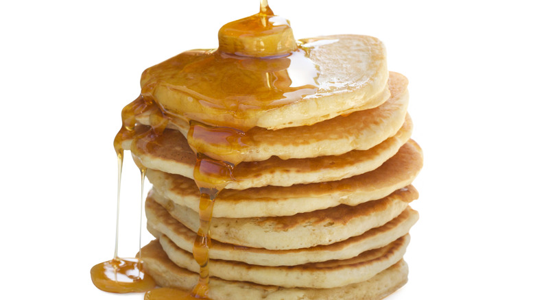 maple syrup poured on stack of pancakes