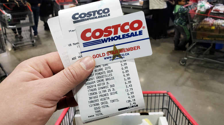 hand holding receipt and costco membership card