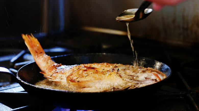 Butter basting fish in a pan.