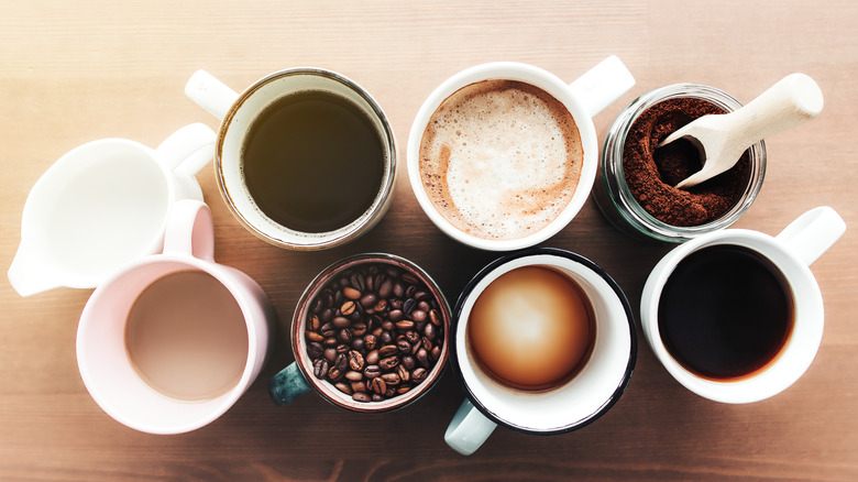 Coffee beans, ground coffee, and several cups of caffeinated beverages on a table