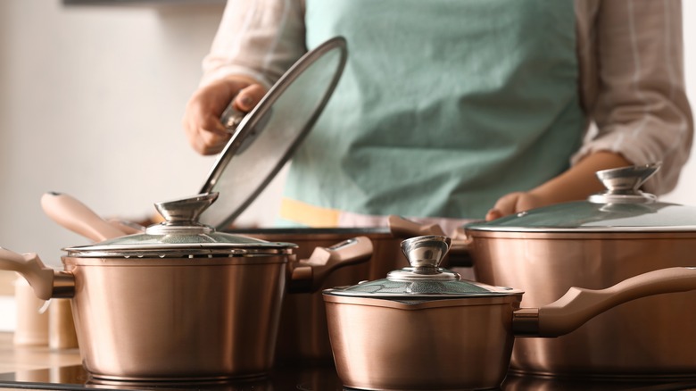 Woman cooking with pots holding lid