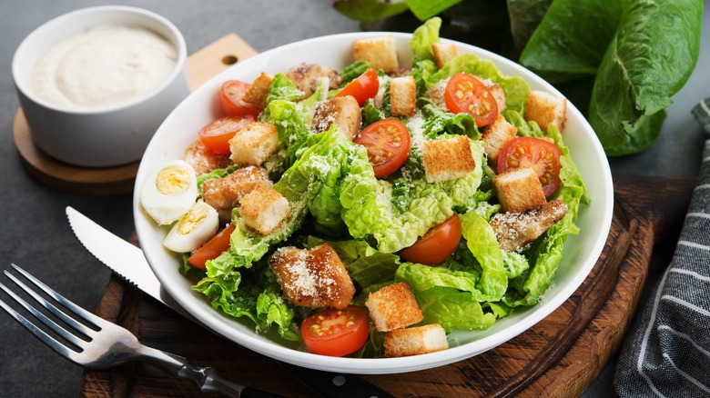 Salad with croutons, tomatoes, and cheese with dressing on the side