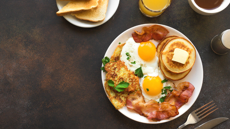 full American breakfast on white plate brown table