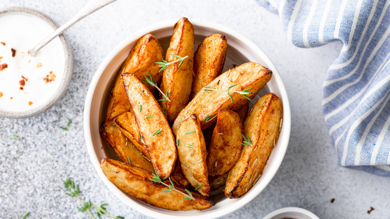 potato wedges in white bowl with rosemary