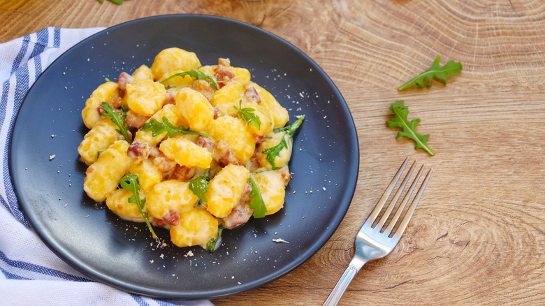 Bowl of gnocchi with lardons and rocket leaves