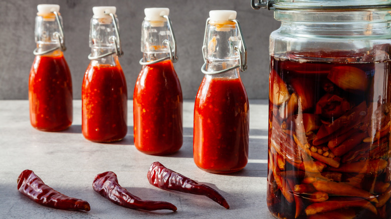 Bottles of hot sauce with a brine and dry peppers