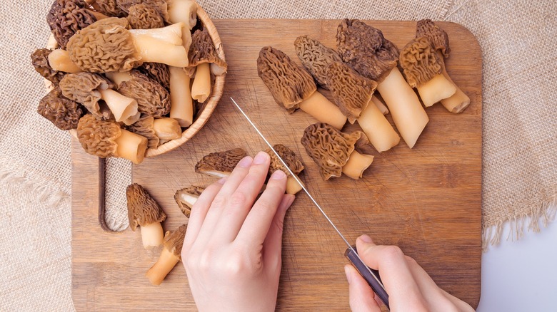 cook slicing morels on wooden cutting board
