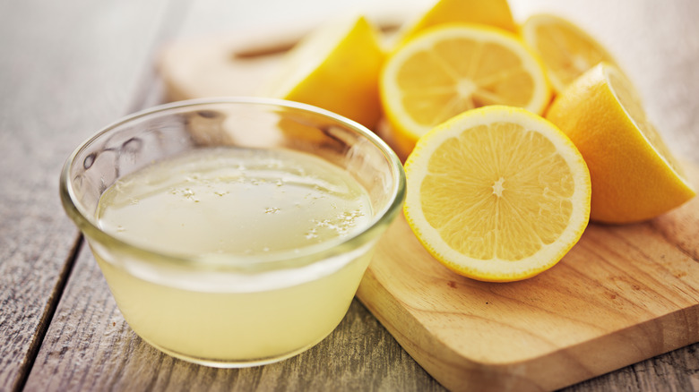 Lemons beside a bowl of lemon juice