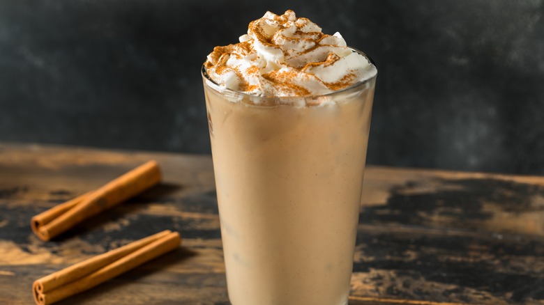 An iced pumpkin spice latte next to cinnamon sticks