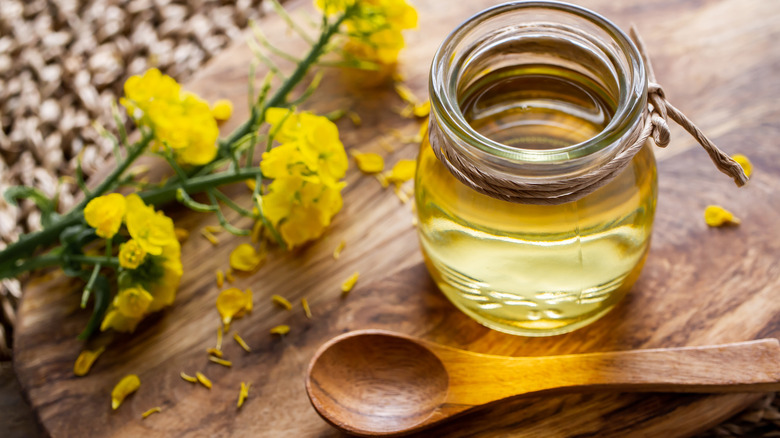 jar of canola oil with wooden spoon and flowers