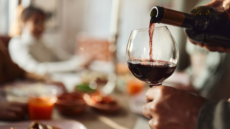 Person pouring a glass of red wine