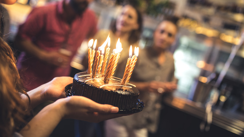 Someone holding chocolate cake with candles