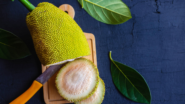 A sliced green jackfruit on a cutting board