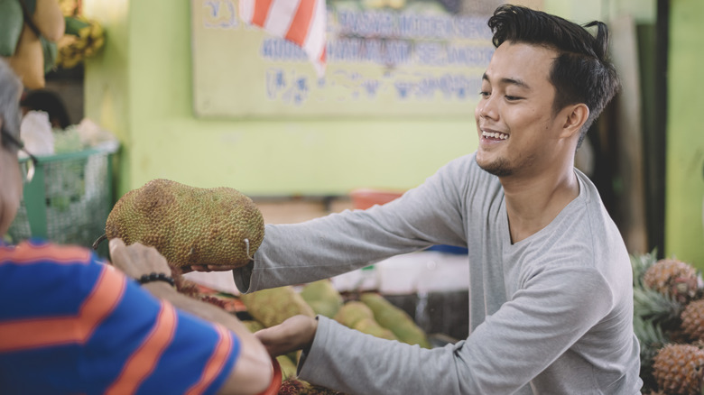 Man buying jackfruit from an Asian food market