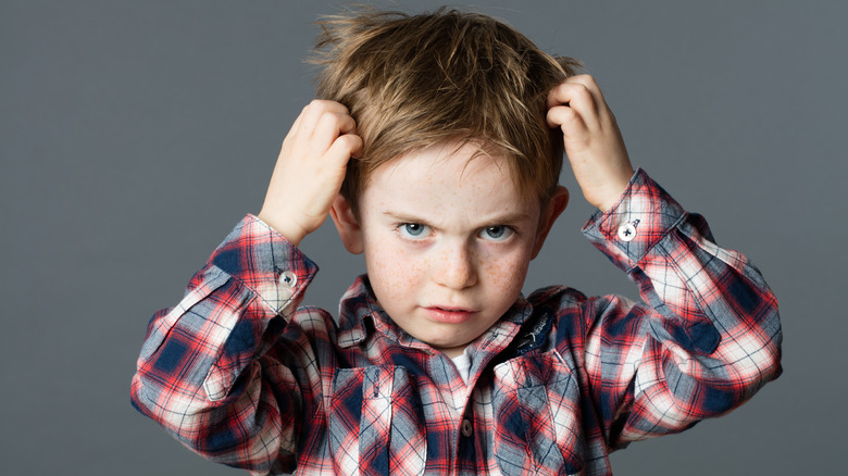 Boy scratching his head