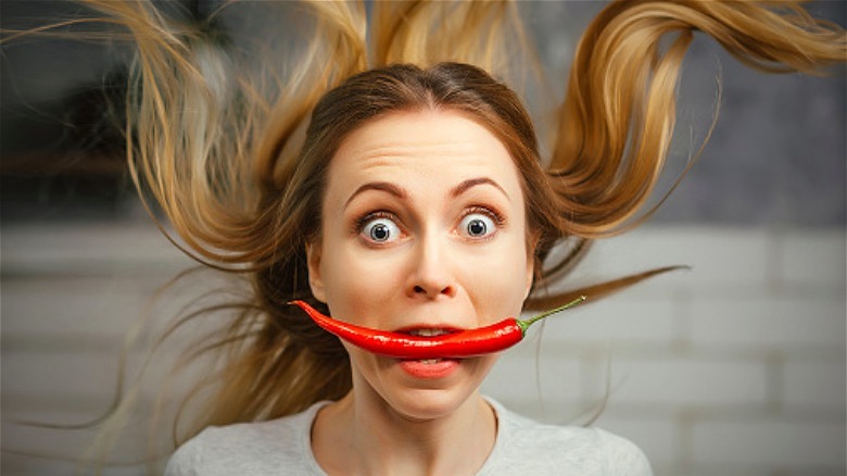 Surprised woman eating red chili pepper 