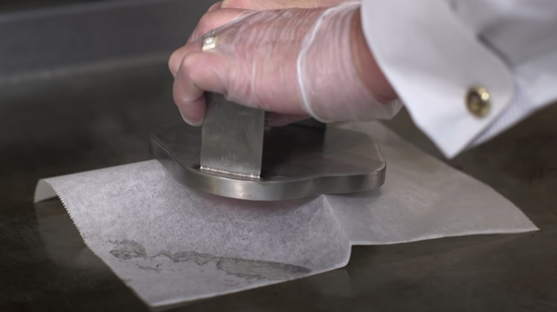 hands mashing a smashburger on griddle 