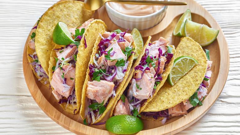 Salmon hardshell tacos with lime wedges