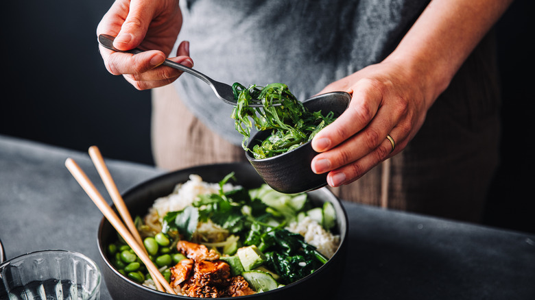 Man making a salad with greens, soybeans, and rice