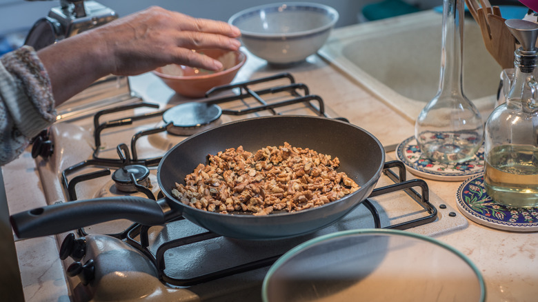 person toasting walnuts on frying pan